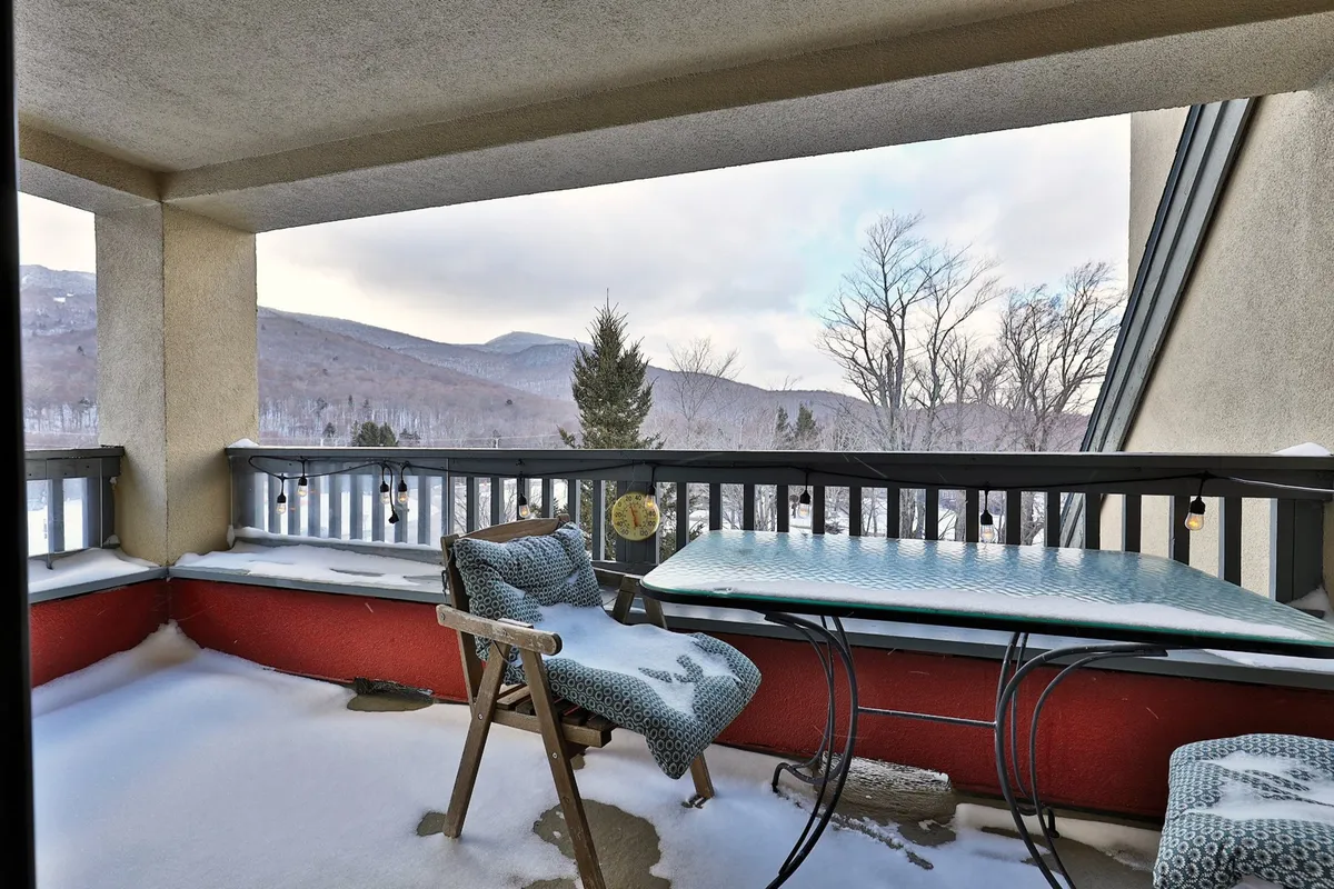 This exterior image captures a table and chair set against a snow-covered ground with breathtaking panoramic mountain views. The scene invites guests to relax outdoors, perhaps sipping a drink as the sun sets behind the hills, evoking the post-ski ambiance and mountain-town atmosphere referenced in the section.