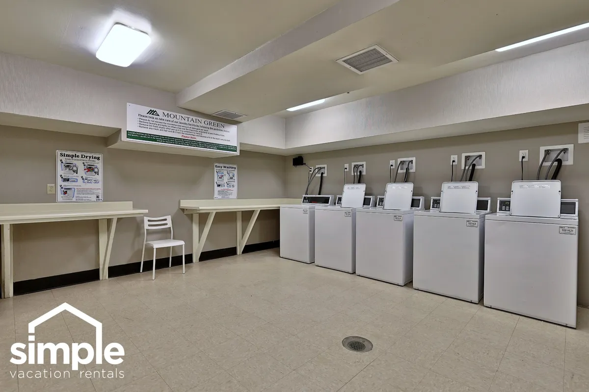 A communal laundry room with multiple washing machines, a dedicated drying area, and an information board on the wall. The environment is clean, practical, and well-organized, making it easy for guests to handle laundry needs during their stay.