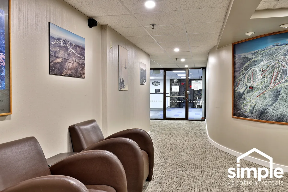 A comfortable seating area with inviting armchairs and tasteful artwork, with glass doors that open to another space, possibly leading outdoors. The decor features nods to local nature, suggesting a transition point for guests heading out to explore or returning from adventure.