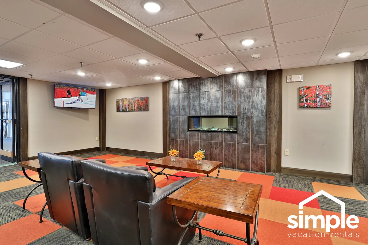 A comfortable seating area is arranged around a fireplace, with a smart TV mounted above, and tasteful artwork adorning the walls. The arrangement suggests a spot for socializing, relaxing, or catching up on shows after a productive day.