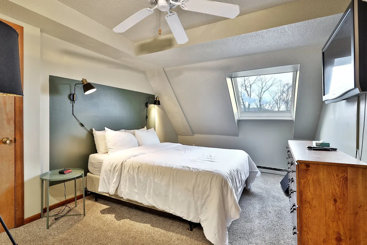 A relaxing bedroom with a comfortable bed, window letting in natural light, a nightstand, and a dresser. The setup evokes tranquility and privacy, perfect for unwinding after an active day.