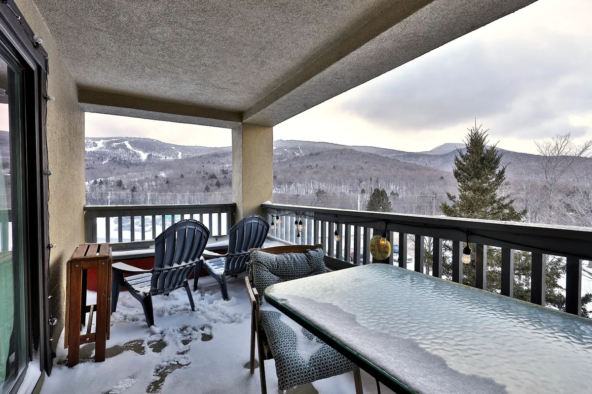 A snow-covered balcony with mountain views and outdoor seating. The scene is tranquil, showing the possibilities for relaxation, though access may be limited during construction.