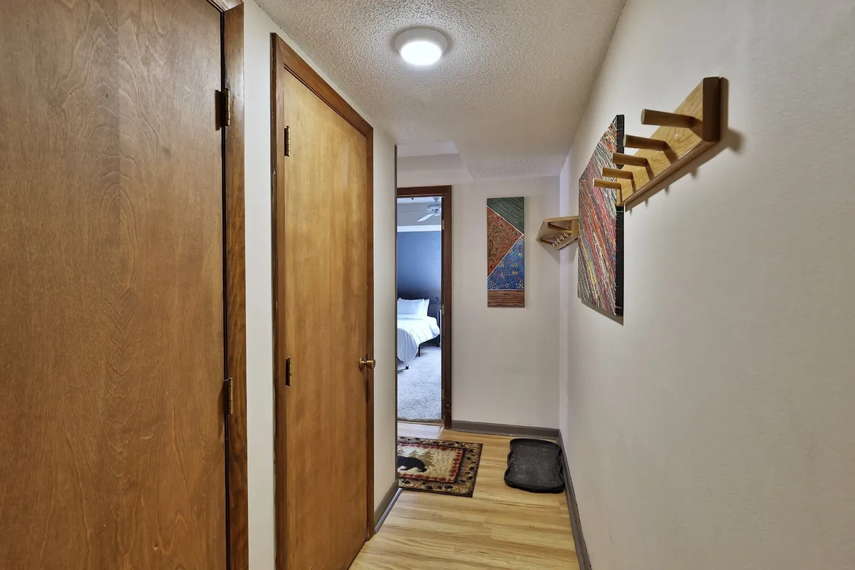 A welcoming entryway with wooden doors and artwork on the wall, offering a glimpse into a cozy bedroom. The scene evokes a sense of privacy and security upon entering the home.